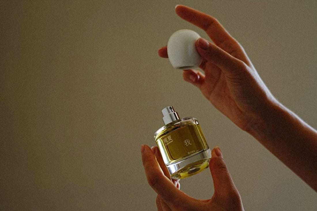 A person's hands holding a tosummer Her Perfume bottle, with the lid held above the bottle, emphasizing the scent of the untamed soul.