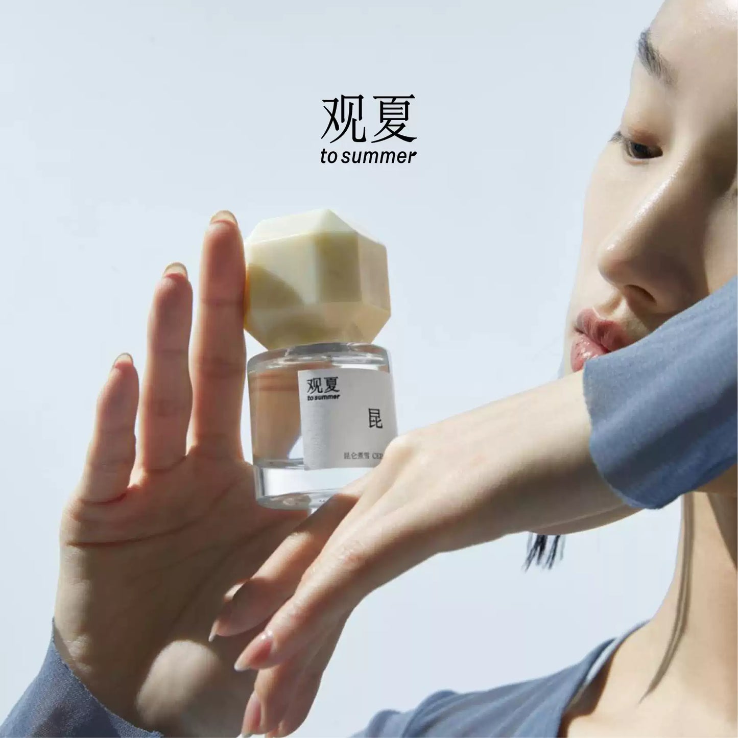 A person holding To Summer Cedarwood perfume under daylight, showing the beige cap and transparent bottle with a serene mood.