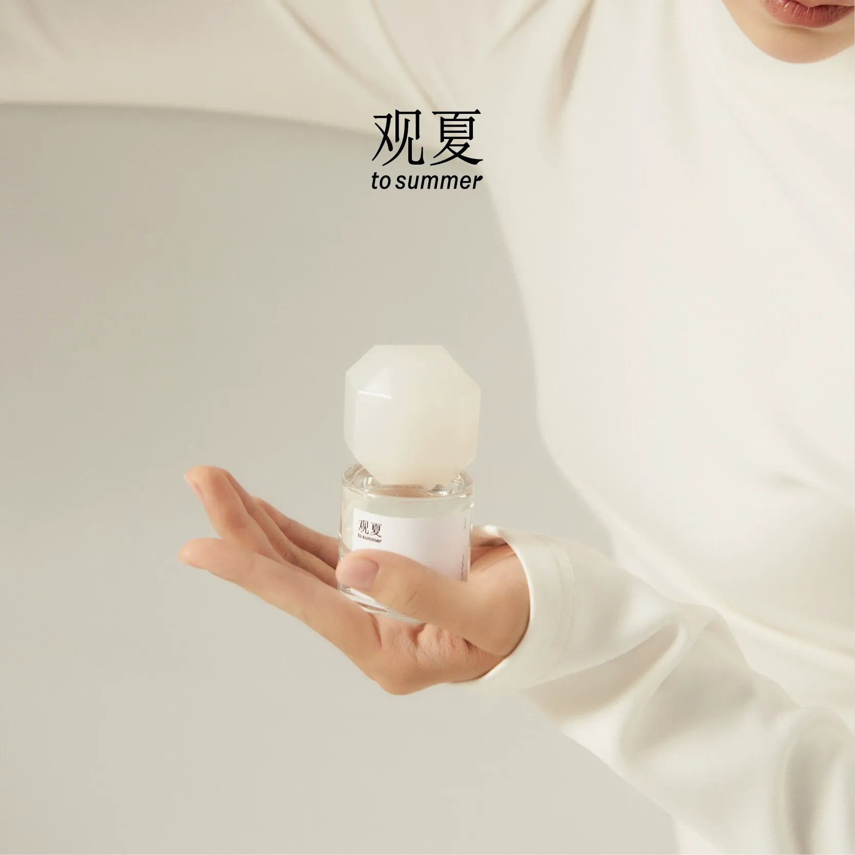 Person in white outfit holding To Summer NUDE perfume, creating a soft minimal look and clean girl aesthetic.