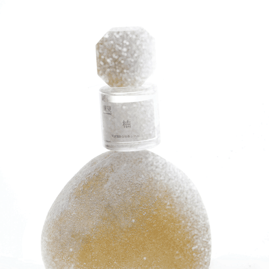 To Summer POMELO perfume bottle covered in real frost on a pomelo fruit, evoking cool citrus freshness and winter vibes.