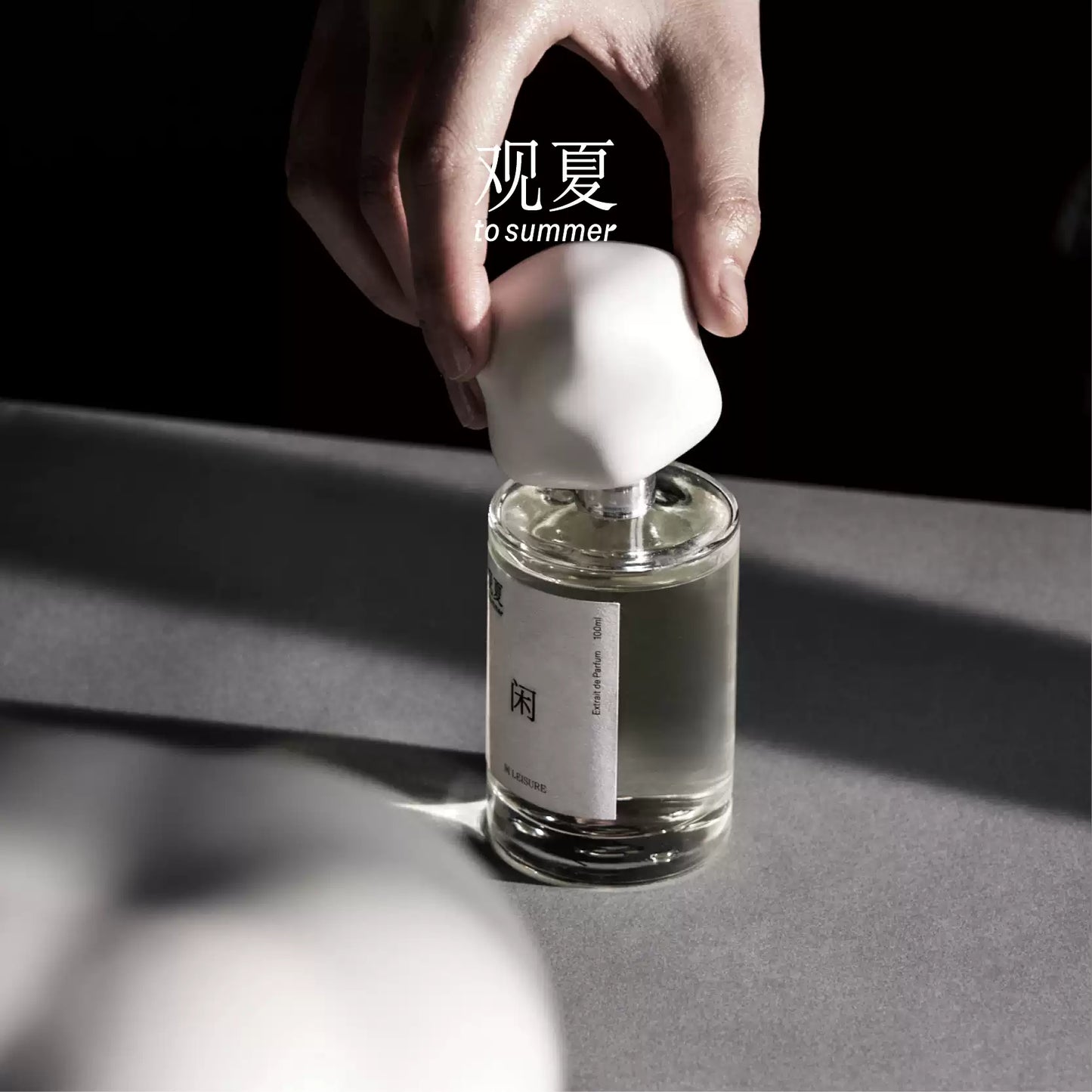 Hand opening To Summer LEISURE perfume bottle, showcasing the minimalist design and craftsmanship.
