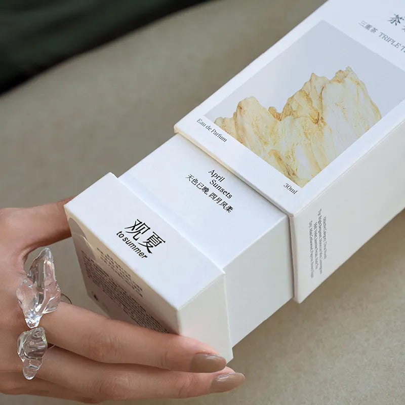 Hand holding the To Summer Triple Tea perfume box, perfect for gifting, featuring a minimalist design and mountain illustration.